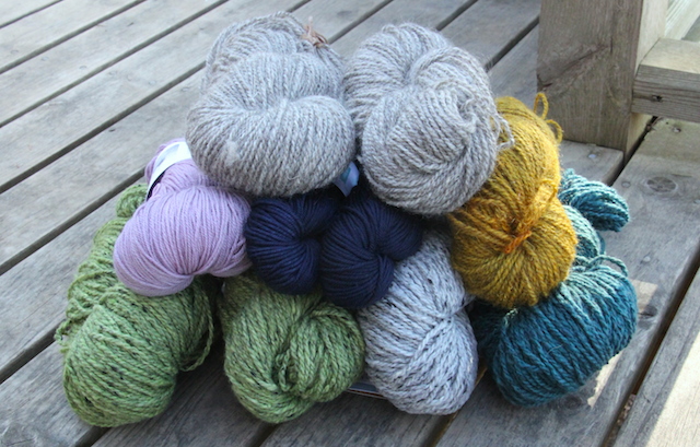 The full haul, l-r, top to bottom:  Two skeins undyed yarn from Marilyn; Swan's Island  Organic Fingering weight in Vintage Lilac, two skeinds Swan's Island Washable DK in Midnight (for a new hat for L), yellow/gold skein from Marilyn; Four skeins Fleece Artist Wool Tweed